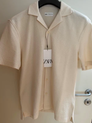 Kortärmad skjorta från Zara - Helt oanvänd kortärmad skjorta från Zara med prislappen kvar i storlek S men jag skulle säga att den är lite större i modellen. 