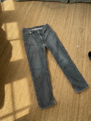 Acne studio jeans - Säljer ett par Acne grå jeans med rak passform och hög midja. Klassisk modell med bälteshällor och dragkedjegylf. Jeansen har en tvättad look och är tillverkade i denim, perfekt för en avslappnad stil.
