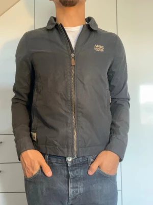 Mörkblå vindjacka från Morris - Marinblå vindjacka från Morris. Strl S. Det finns en innerficka (se bild 4) utöver de två på framsidan. Modellen är 178 cm och väger 77 kg. Hör gärna av dig vid frågor!