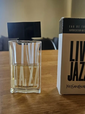 Yves Saint Laurent Live Jazz Eau de Toilette 50ml - Live Jazz från Yves Saint Laurent är en Eau de Toilette med en volym på 50 ml. Slutad tillverkad sen många år sen och är sällsynt. Köptes ny i förpackning från Ebay i april 2024 av en italiensk säljare. Ca 30/50 ml kvar. Denna batch är troligen från sent 90 tal när den lanserades.