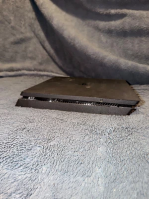 Svart spelkonsol, tunn design - Säljer en svart spelkonsol med platt och tunn design. Konsolen har en fyrkantig form och är tillverkad i plast. Perfekt för dig som gillar gaming och vill ha en stilren konsol till din setup.