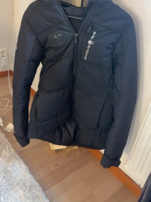 Svart pufferjacka från Sail Racing - Säljer en svart pufferjacka från Sail Racing med dragkedja framtill och logga på bröstet. Jackan har lång ärm, hög krage och två sidofickor med dragkedja. Perfekt för kyliga dagar och riktigt snygg nu till vintern. 