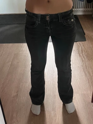 Svarta bootcut jeans med vita sömmar - Snygga svarta jeans med bootcut-modell och kontrasterande vita sömmar. Jeansen har fem fickor, bälteshällor och knappgylf. Materialet är klassisk denim med lite stretch.💕