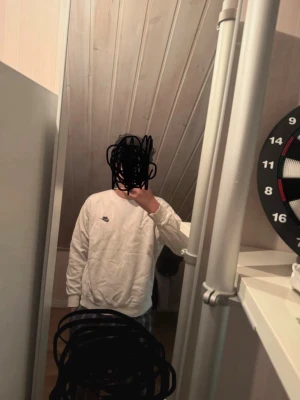 Vit långärmad tröja från Nike - Vit långärmad sweatshirt från Nike med rund halsringning och svart Nike-logga på bröstet. Tröjan har en klassisk passform och är tillverkad i mjukt material som passar perfekt till en avslappnad stil i storlek medium.