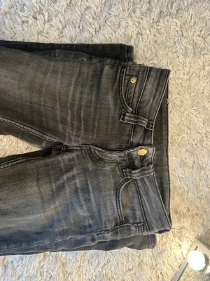 Grå tvättade jeans från Cheap Monday - Säljer ett par grå tvättade jeans från Cheap Monday med klassisk femficksmodell och guldfärgade knappar. Jeansen har en smal passform och tydliga slitningar för en cool, avslappnad look. Perfekta till vardags för en trendig stil.