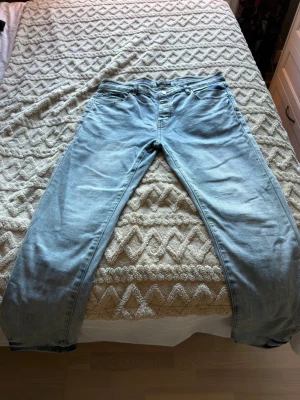 Ljusblå jeans från Purple Brand - Säljer ett par ljusblå jeans från Purple Brand med klassisk femficksmodell och raka ben. Jeansen har snygga slitningar och kontrastsömmar som ger en avslappnad vibe. Perfekta till sneakers och hoodie för en chill look.