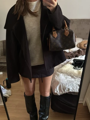Svart oversized ullkappa - Säljer en svart oversized kappa med bred krage och knäppning framtill. Kappan har en avslappnad passform och är tillverkad i ett tjockare ullmaterial som passar perfekt för kyligare dagar. Enkel och stilren design som är lätt att matcha.