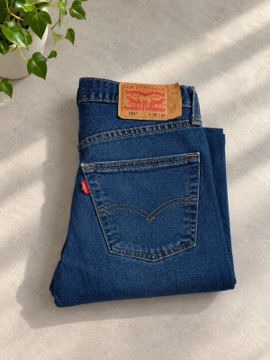 Levi's 501 blå raka jeans - Klassiska blå Levi's 501 jeans med rak passform och fem fickor. Jeansen har den ikoniska läderlappen bak i midjan och röd Levi's-tag på bakfickan. Tillverkade i slitstark denim med snygga kontrastsömmar.