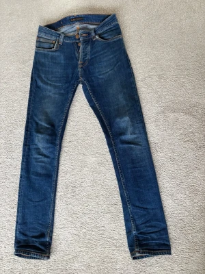Nudie Jeans modell Grim Tim  - Säljer ett par Nudie jeans modell Grim Tim färg indigo myth i storlek 27, 30. Fint skick, på framfickorna är det dock två trådar som är lite lösa men de stör inte eller försämrar jeansen men det är fortfarande ett slitage.