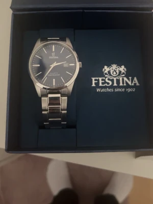 Festina silverklocka med blå urtavla - Stilren klocka från Festina med blå urtavla och datumvisning. Armbandet är i blankt silverfärgat metall och klockan har en klassisk rund form. Perfekt accessoar för dig som gillar en tidlös look.
