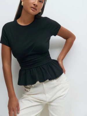 Svart topp med volang  - Snygg svart topp med korta ärmar, rund halsringning och markerad midja med rynkdetaljer. Nedre delen har en volangkant som ger en feminin touch. Perfekt att styla med både jeans och kjol för en trendig look.