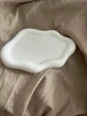 Vitt vågformat fat i keramik - Unikt vitt fat i keramik med vågformade kanter och organisk form. Perfekt som dekoration eller förvaring av småsaker. Passar snyggt på skrivbordet eller i hallen för nycklar och smycken.