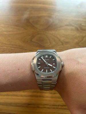 Seiko Nautilus Brun Mod DEFEKT - *DEFEKT*Snygg Seiko Nautilus-homage mod med automatiskt urverk. Klockan är helt ny, aldrig använd och i nyskick. Den har en stilren design inspirerad av Nautilus och passar lika bra till vardags som vid finare tillfällen med den exklusiva bruna färgen på urtavlan. Diametern är 41mm.  Materialet är robust rostfritt stål. Klockan är en Seiko Mod, Dvs en seiko klocka, men med eftermarknads armband och case.