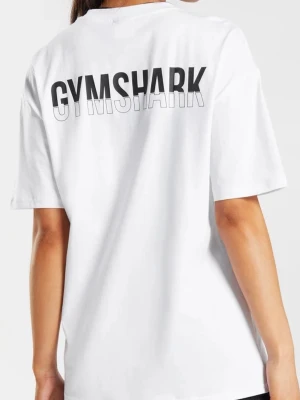 Vit oversized t-shirt från Gymshark - Säljer en vit oversized t-shirt från Gymshark med stor logga på ryggen och liten logga framtill. T-shirten har korta ärmar och är gjord i mjuk bomull, perfekt för en avslappnad och sportig stil.