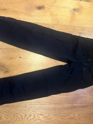 Svarta mjukisbyxor med dragsko - Säljer ett par svarta mjukisbyxor med dragsko i midjan och fickor på sidorna. Byxorna har en avslappnad passform och är perfekta för chill dagar. Tillverkade i mjukt material som känns skönt mot huden.