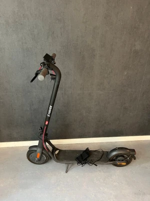 Elsparkcykel navee v25 - Detta är en svart elsparkcykel av modellen Navee V25.Den har en maximal räckvidd på cirka 25 km och en topphastighet på 20 km/h.Fordonet har en hopfällbar design, handbroms och en inbyggd display på styret 