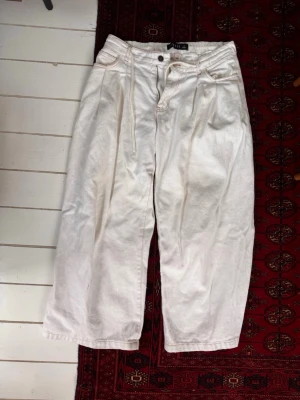 Lioness vita jeans low rise o baggy  - Säljer ett par vita jeans med  breda ben. Jeansen har klassisk femficksdesign och synliga sömmar. Passar perfekt för en avslappnad och trendig stil. Materialet är kraftigt denim i bomull. Kan passa flera storlekar eftersom den är adjustable