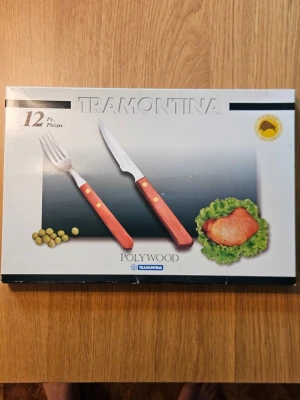 Bestickset 12 delar Tramontina, NYTT  - Aldrig använda, 12-delars bestickset från Tramontina med sex gafflar och sex knivar. Handtagen är i rödbrunt träliknande material med mässingsfärgade nitar. Perfekt till grillkvällar eller middagar där du vill ha snygga och tåliga bestick.