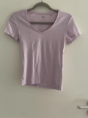 Ljuslila v-ringad t-shirt - En stilren ljuslila t-shirt med v-ringning och korta ärmar. Perfekt basplagg i mjuk bomull som passar till det mesta. Enkel och snygg design som är lätt att matcha.