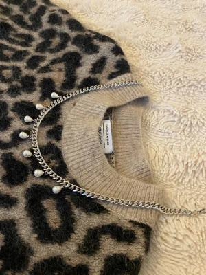 Silverfärgat halsband med pärlor - Snyggt halsband i silverfärgad rostfritt med sju små vita pärlor som hänger längs kedjan. Kedjan har en klassisk, lite chunky design och pärlorna ger en elegant touch. Perfekt accessoar för att lyfta vilken outfit som helst.