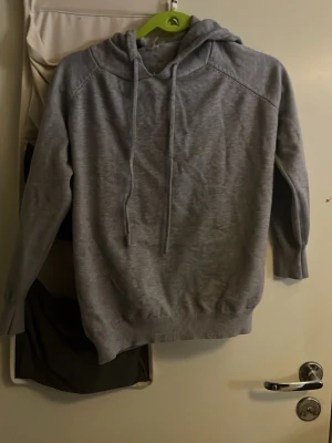 Ljusgrå hoodie med huva - Säljer en stilren ljusgrå hoodie med huva och dragsnören. Hoodien har långa ärmar, ribbade muddar och nederkant. Perfekt för en avslappnad look och passar till det mesta. Materialet känns mjukt och bekvämt mot huden. Har använt den två tre gånger för den passade inte min stil.    Storken är 160cm