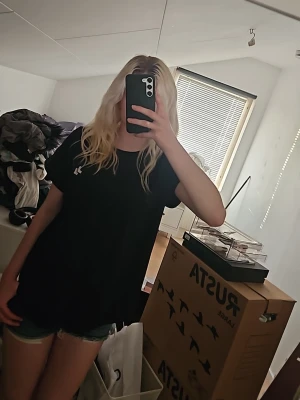 Svart sportig t-shirt med tryck - Säljer en svart sport-t-shirt med rund hals och korta ärmar. T-shirten har en vit logga på bröstet och vid halsen. Materialet känns lätt och andas, perfekt för träning eller gym. Passar dig som gillar en enkel och stilren look. Knappt använt