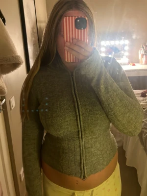 Grå zip hoodie i mjukt material - Mysig grå zip hoodie med lång ärm och figurnära passform. Tröjan har dragkedja framtill och är tillverkad i ett mjukt, stretchigt material som känns skönt mot huden. Perfekt för en avslappnad och trendig look. Den och också luva 