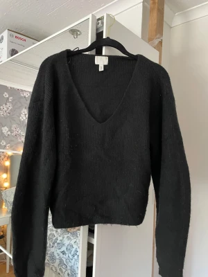 Svart stickad tröja från H&M - Säljer en svart stickad tröja från H&M med djup v-ringning och långa ärmar. Får inte användning av den längre