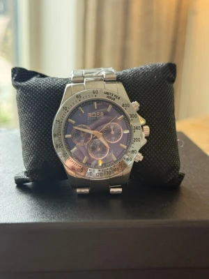 Silverfärgad klocka  - Stilren klocka med silverfärgat armband i metall och mörkblå urtavla. Klockan har kronograf-funktion, tydliga markeringar och flera små urtavlor. Perfekt accessoar för dig som gillar en klassisk och elegant look.
