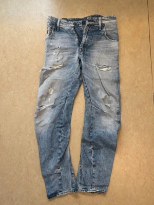 Blå baggy-jeans från G-STAR - Blå baggy-jeans från G-STAR med slitningar.