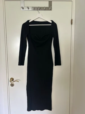 Svart långärmad ribbad klänning - Säljer en svart långklänning med ribbad struktur och lång ärm. Klänningen har en snygg v-ringad urringning och sitter figurnära. Perfekt för dig som gillar stilrena och trendiga plagg.