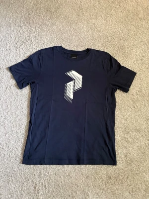 Peak Performance T-shirt  - Marinblå T-shirt från Peak Performance i storlek 170 juniorstorlek. Stor Peak Performance-logga framtill i vitt. Sparsamt använd och i bra skick utan hål eller tydligt slitage.  📦 Snabb leverans! 💬 Hör gärna av dig vid frågor eller om du vill ha fler bilder/mått!