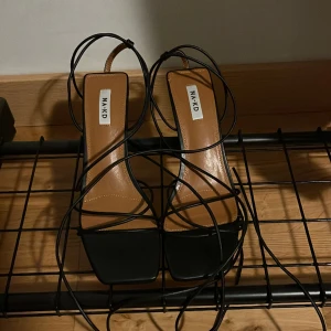 Högklackade skor  - Högklackade skor med snörning från NA-KD. Aldrig använda då jag tycker mina fötter inte riktigt passat i skorna.  Klackhöjd 7,5