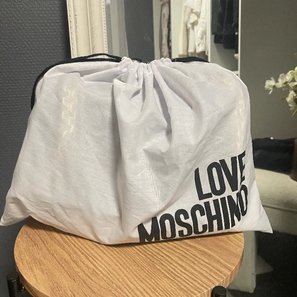 Helt oanvänd Moschino väska! Längd: 33 cm Höjd: 23,5  Djup: 12, 5 cm . Det finns tre fack och en med dragkedja. Väskan stängs med magnet knapp 🥰🥰 Köpt för ca 3000kr . Väskor.