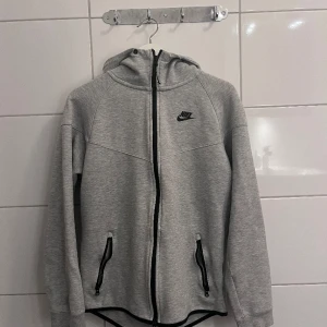 Grå Nike Tech Fleece - Näst intill ny endast använd ungefär 10 gånger. Ny pris 1200 kr. Väldigt skönt material. Storlek S.