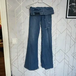 Ett par jeans med två hål i knät som är använd några gånger men ser nya ut