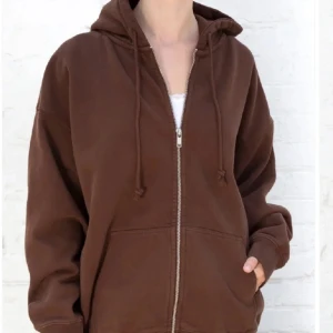 Brandy Melville: Christy hoodie i färgen brun. - Brun brandy Melville kofta som är oversized. Den är i helt nytt skick och endast använt ett par gånger. Original pris är 460kr.