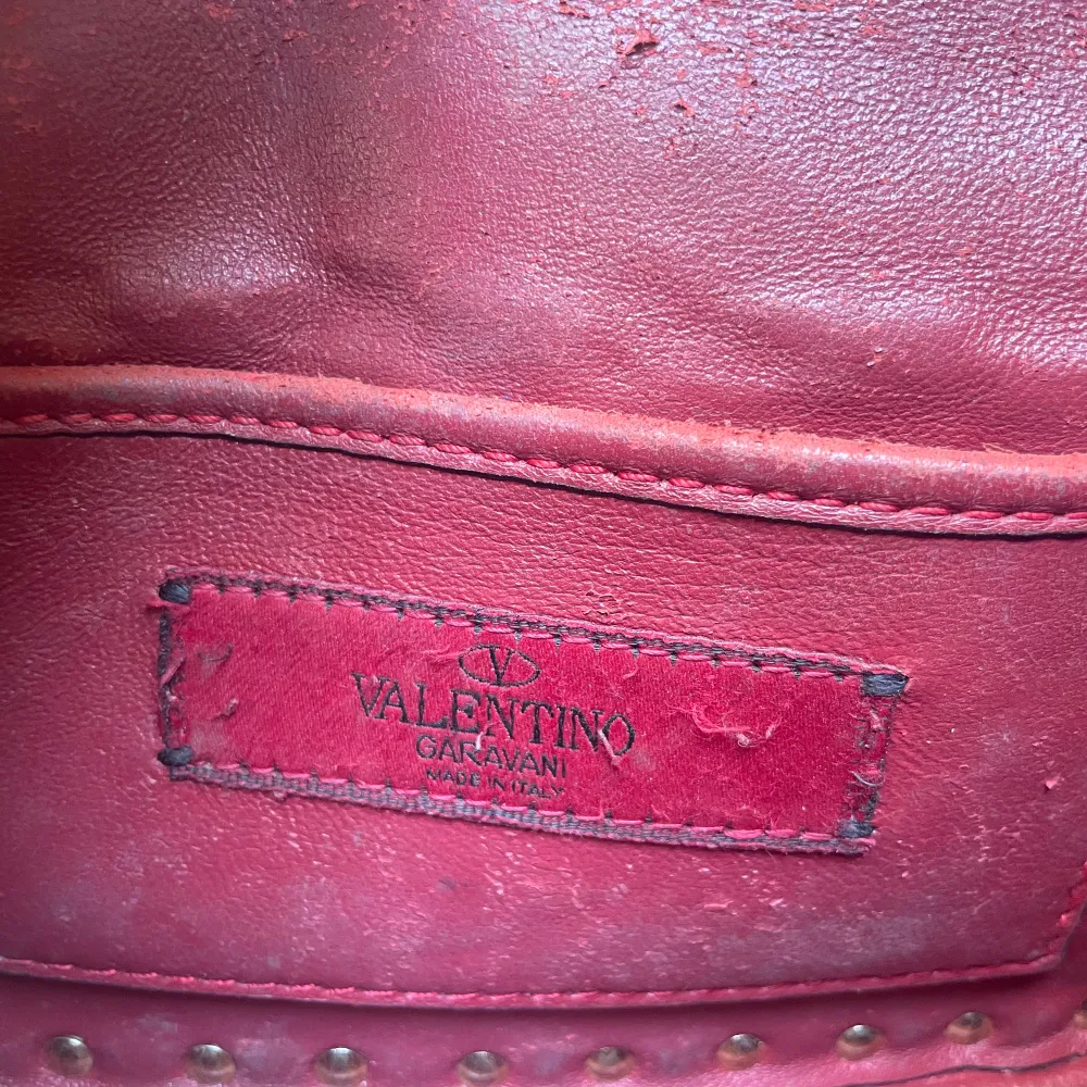 Säljer min äkta Valentino väska i röd. Det finns tydliga tecken på användning inuti i väskan, samt vid fästet för kedjan som jag har lagat hos en skomakare. Till utseendet finns inga tydliga defekter som man tänker på. Dustbag samt äktahetstagar!. Väskor.