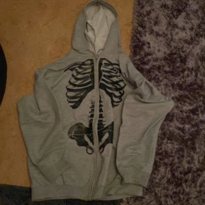 Grå zipupp hoodie  - Köpt på Plick, nästan aldrig använd, skelett tryck bak och fram, storlek s/m