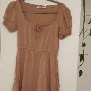 Brunrosa sommarklänning - En klänning som "rör sig fint". Elastisk i midjan. Använd max 2 gånger.