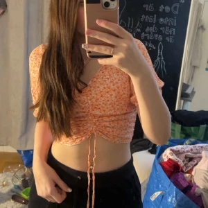 Orange blus  - Orange blommig blus med snörning, osäker på storlek och märke. Passar s. Köpare står för frakt 
