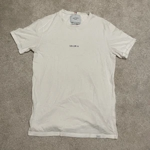 Les Deux Vit Fin T-shirt (Stl. Medium): Sofistikerad Elegans till Originalpris 600 kr - En vit Les Deux T-shirt, storlek Medium, mycket bra passform. Ett märkesplagg som ursprungligen kostar 600 kr, perfekt för en elegant och stilig look.