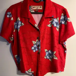 Röd hawaiiskjorta i form av en crop-top som man kan knyta. Köpte second hand men har aldrig själv använt den