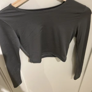 Grå lång armad tröja i glansit matrial  - En grå långarmad tröja i jätte skönt tyg lite kortare i längden men blir längre när man sätter på sig den en på galjen säljer pågrund av att den inte kommer till användning den är även i nytt skick har använt 1-2 gånger 