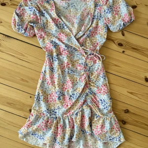 Blommig omlottklänning - För vacker blommig omlottklänning från Gina Tricot🌸Alldeles underbar på sommaren, med dess blommiga mönster och svala tyg. Använd ett fåtal gånger, inga defekter. Hör av dig vid frågor!🫶