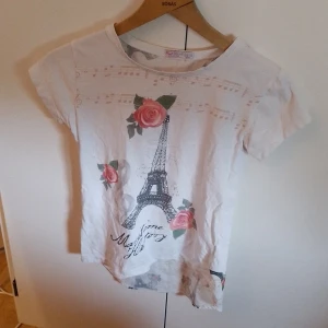 Vit T-shirt Med Bild Barn - En lite längre t-shirt i storlek 152 från peri masali med en bild av eiffeltornet    Katt finns i hemmet