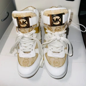 MICHAEL KORS Nikko sneakers  - Begagnade men sparsamt använda fortfarande fina,MICHAEL Michael Kors NIKKO Sneakers och high-top sneakers beige/camel/guld MK111S005-F11  Hälform: kilklackhöjd: 6,5 cm  Säljes i befintligt skick 