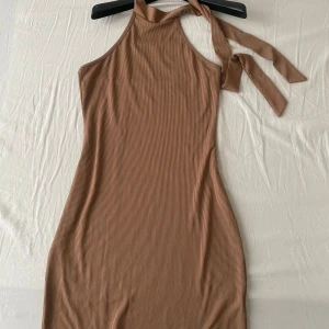 Brun miniklänning - Ribbad brun klänning. Aldrig använd men perfekt till stranden eller allmänt till sommaren.
