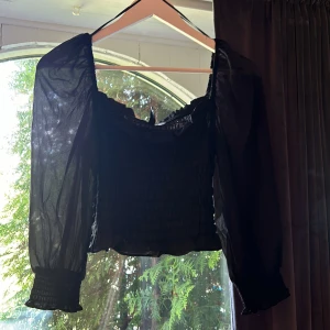 Svart topp - Säljer en svart topp från H&M. Den är croppad och har tunnare material på armarna.