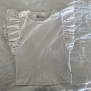 topp med volang - topp med volang på axeln från zara, aldrig använd och i nyaste skick. pris kan diskuteras, skriv privat för fler bilder.